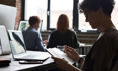A person looking out a window from their desk, taking a short break.