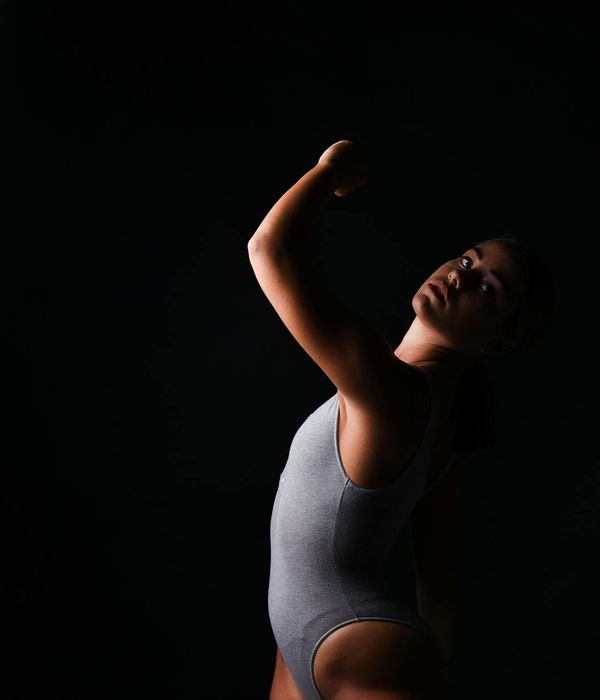 Silhouette of a person stretching against a simple background, conveying movement and flexibility.